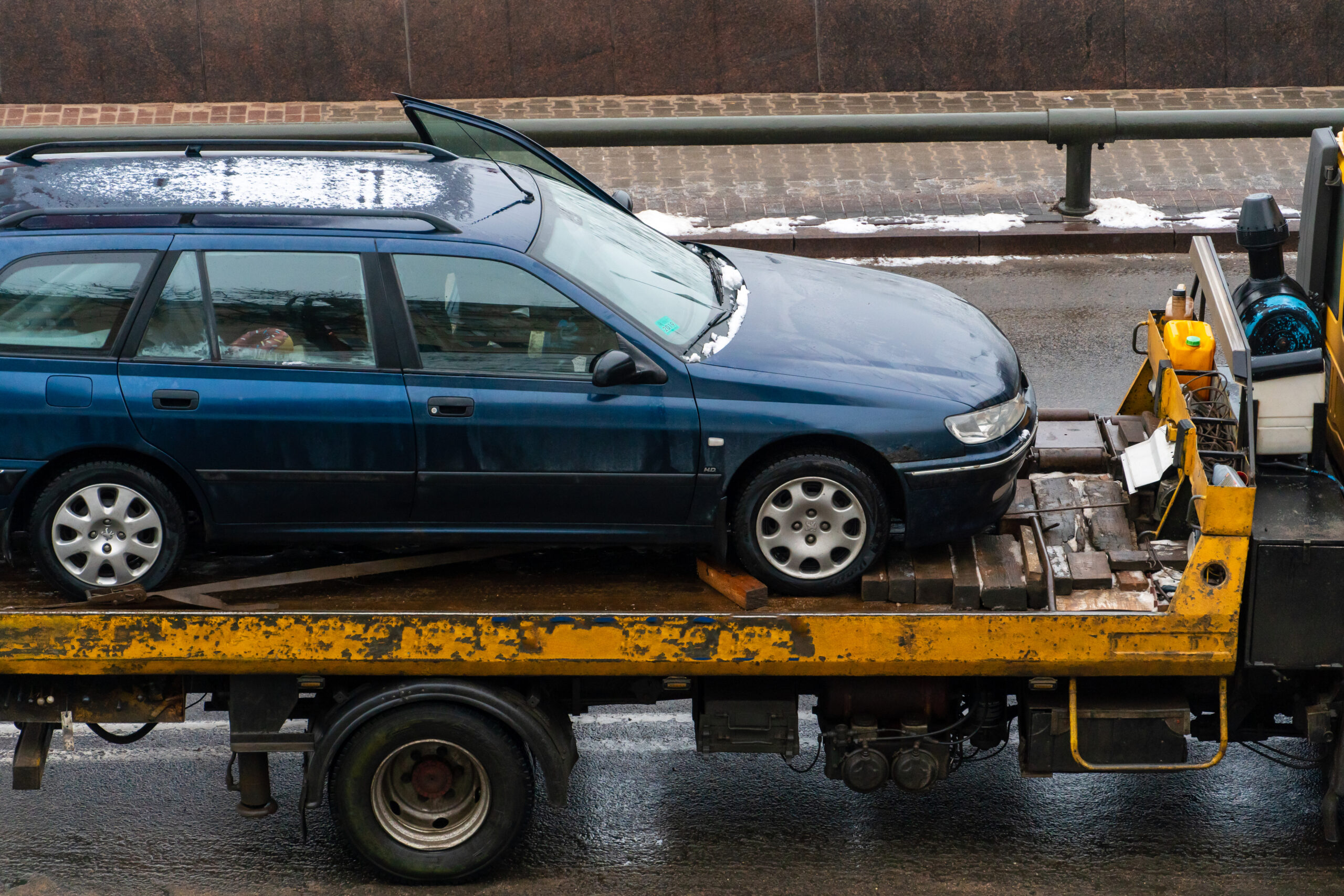 A tow truck on the road with a broken car on a trailer. An accident on the road in the city. Evacuation of a broken car after an accident.